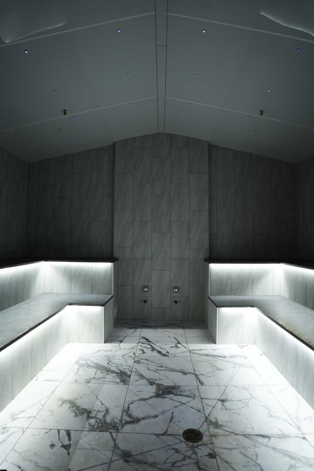 Luxury steam room with heated marble benches and starry ceiling at Fusion Spa & Resort.