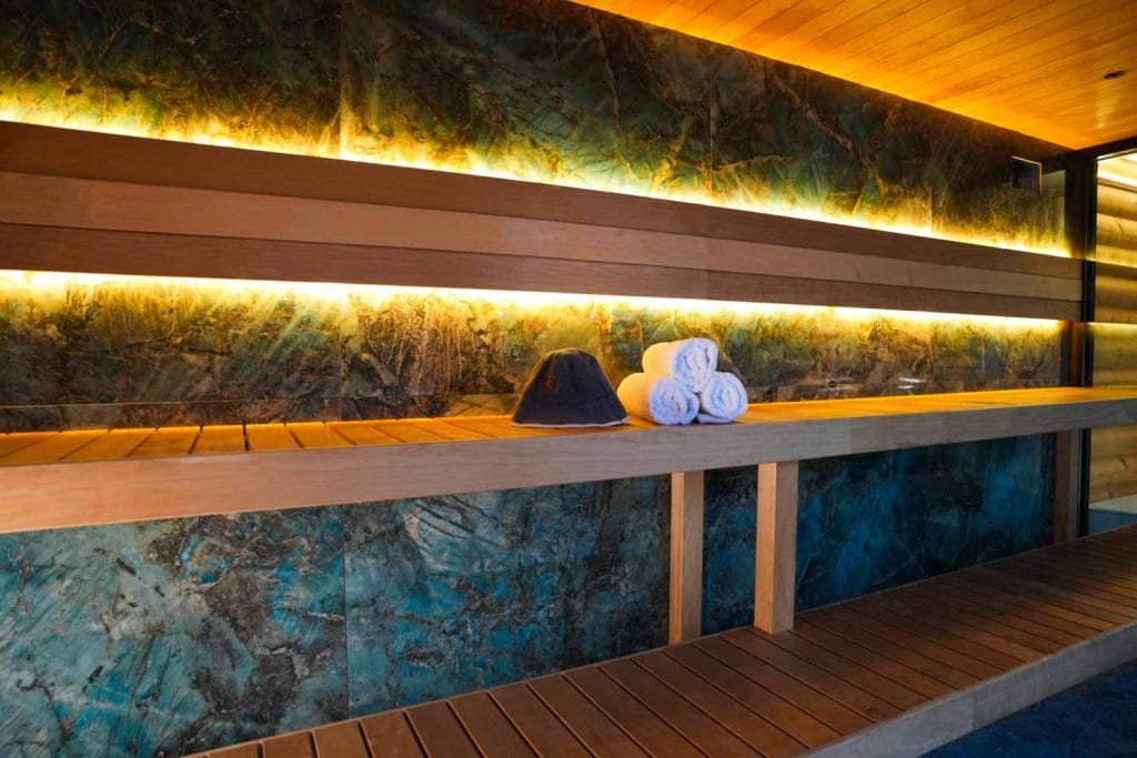 Interior of the Finnish dry sauna at Fusion Spa & Resort featuring warm wooden benches, ambient lighting, and folded towels for guest comfort.